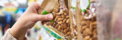 Hand grabbing a bag of almonds from a grocery store shelf
