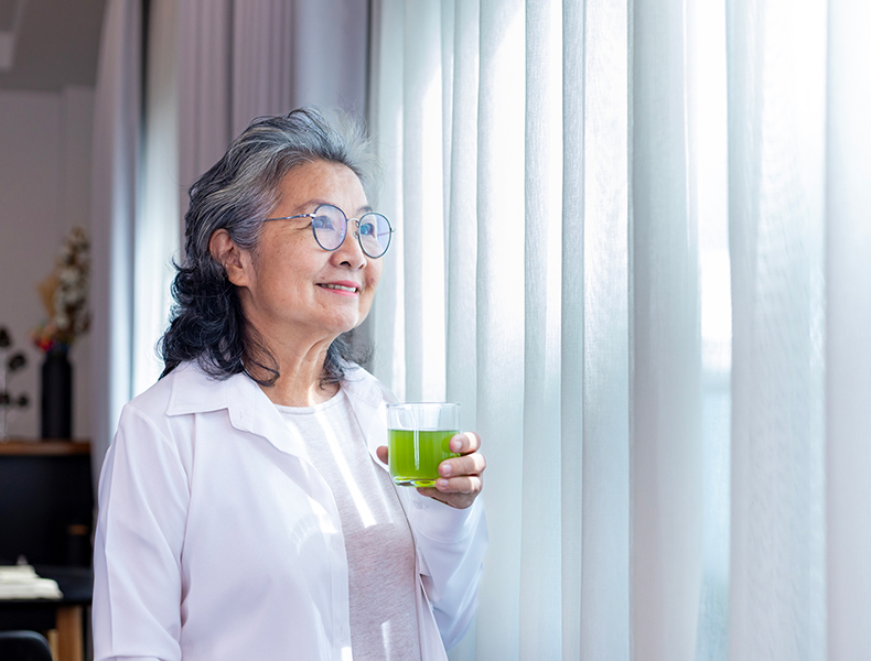 Senior drinking glass of herbal supplement drink