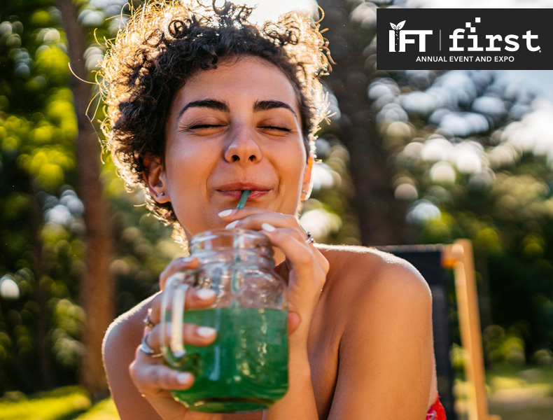 Beautiful young woman in a red dress dancing drinking green juice from a jar