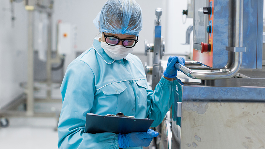 Masked person looking at a clipboard and conducting a food safety inspection.